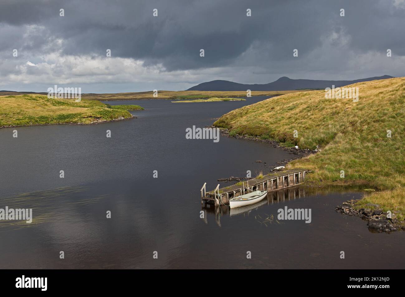 Nuvole pesanti sopra il lago soleggiato e il molo delle barche a Magic Light, Uist, North Uist, Ebridi, Ebridi esterne, Western Isles, Scozia, Regno Unito Foto Stock