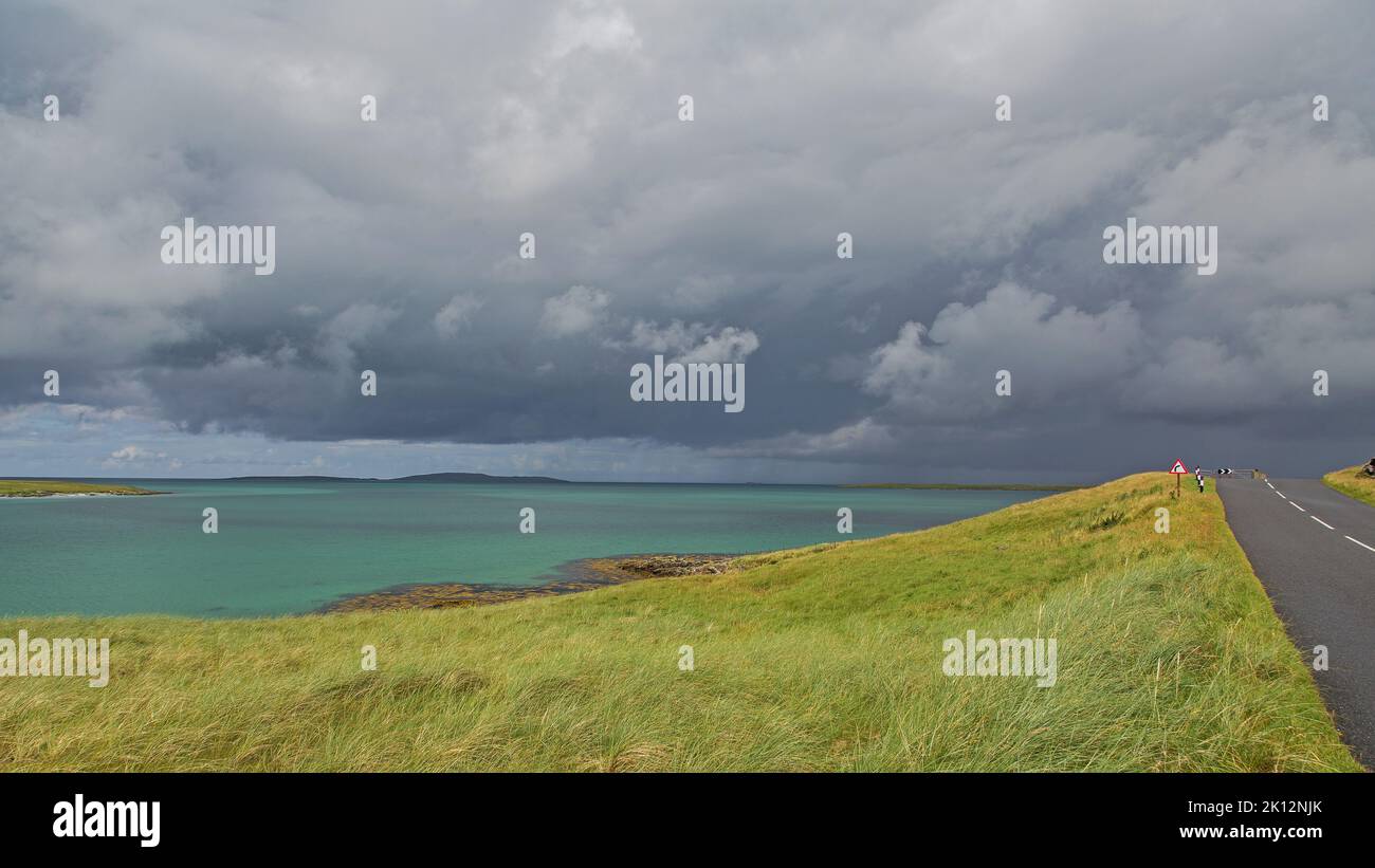 Nuvole di tuono su Sunny Road vicino al mare, Uist, Nord Uist, Ebridi, Ebridi esterne, Western Isles, Scozia, Regno Unito, Gran Bretagna, Foto Stock