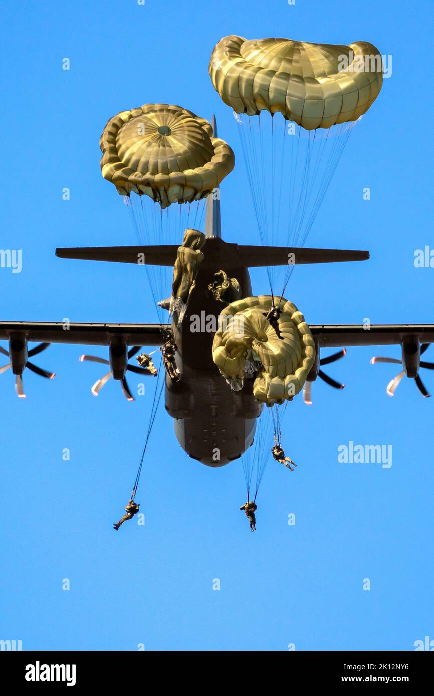 Paracadutisti militari paracadutisti paracadutisti che saltano fuori da un aereo di forze aeree in una giornata di cielo blu chiaro. Foto Stock