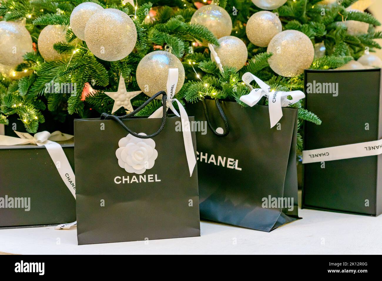 Mosca, Russia - 15 dicembre 2021 - logo Chanel su sacchetti di carta nera con regali sotto l'albero di natale. Lussuoso marchio di abbigliamento, accessori e cos Foto Stock