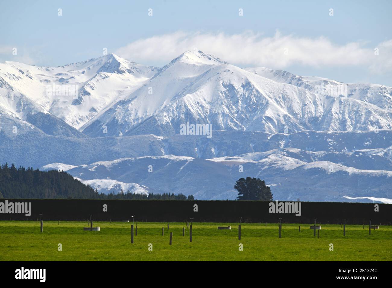 Paesaggio iconico a Canterbury, Nuova Zelanda, con una fattoria con attrezzi per l'irrigazione e la Torlesse Range irrorata da una rara nevicata primaverile nel Foto Stock