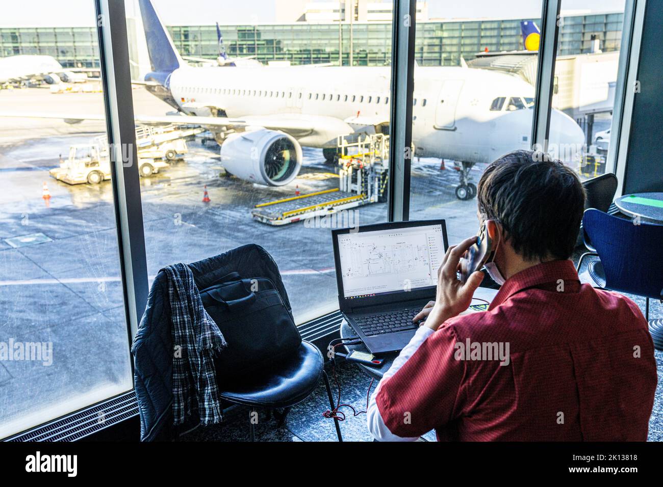 Vista posteriore di un uomo maturo che utilizza un computer portatile e uno smartphone mentre attende in aeroporto, Norvegia, Scandinavia, Europa Foto Stock