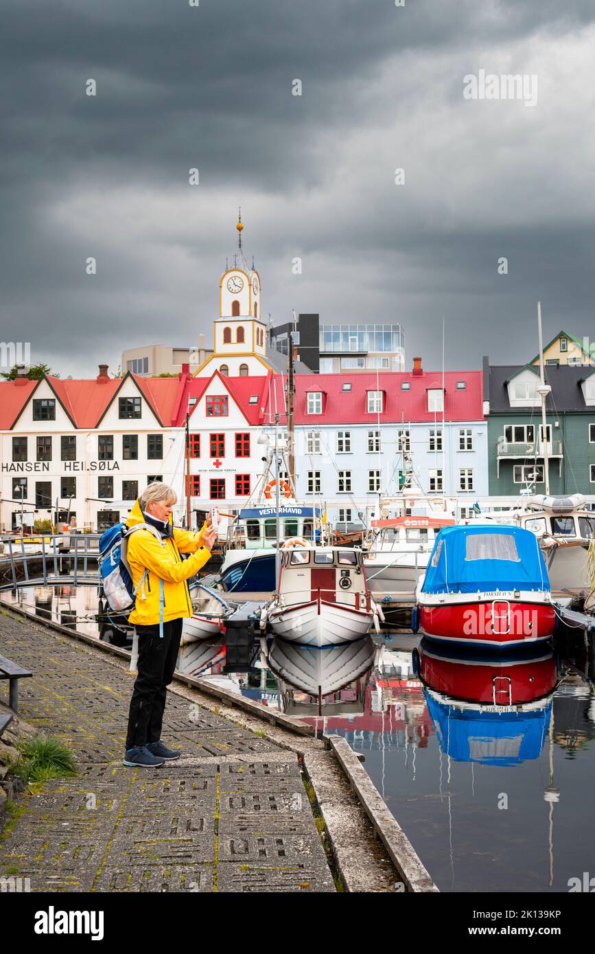 Un turista scatta foto con uno smartphone dal molo del porto di Torshavn, l'isola di Streymoy, le isole Faroe, la Danimarca, l'Europa Foto Stock