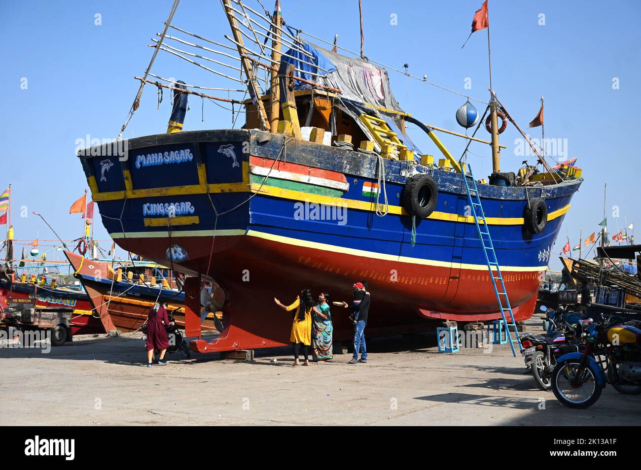 La famiglia di armatori esegue puja su una nuova barca facendo stampe a mano lungo il suo scafo prima del lancio della nubile, Vanakbara, Gujarat, India, Asia Foto Stock