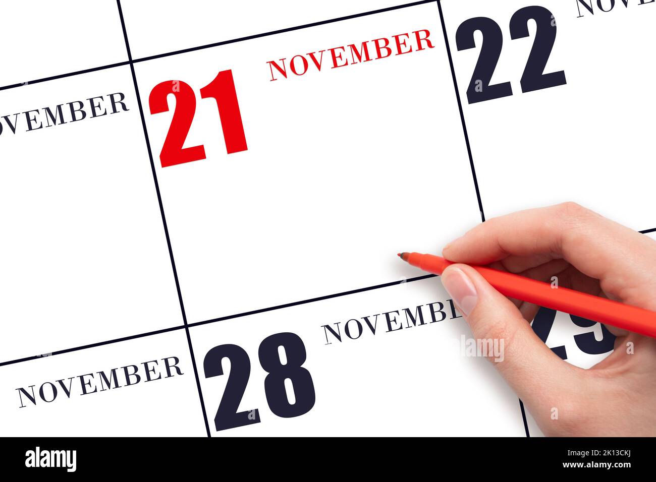 21st° giorno di novembre. Una mano che tiene una penna rossa e indica la data del calendario novembre 21. Data calendario rossa, spazio copia, mockup. Mese autunnale, giorno Foto Stock
