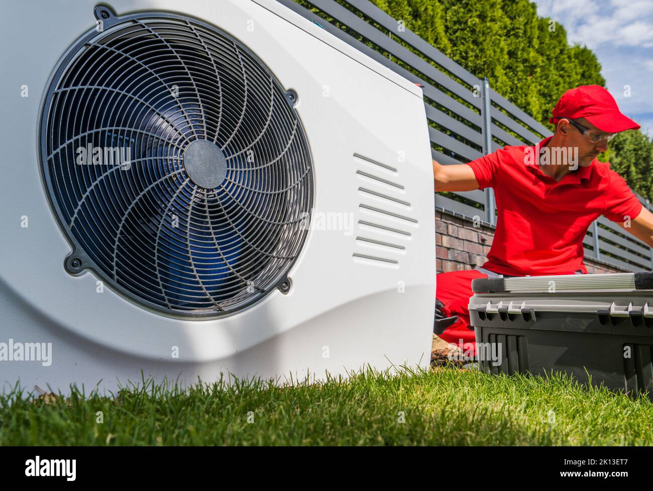 Lavoratore HVAC professionista nel suo 40s Installazione della pompa di calore piscina dispositivo di riscaldamento dell'acqua all'aperto. Tecnologie di risparmio energetico. Foto Stock