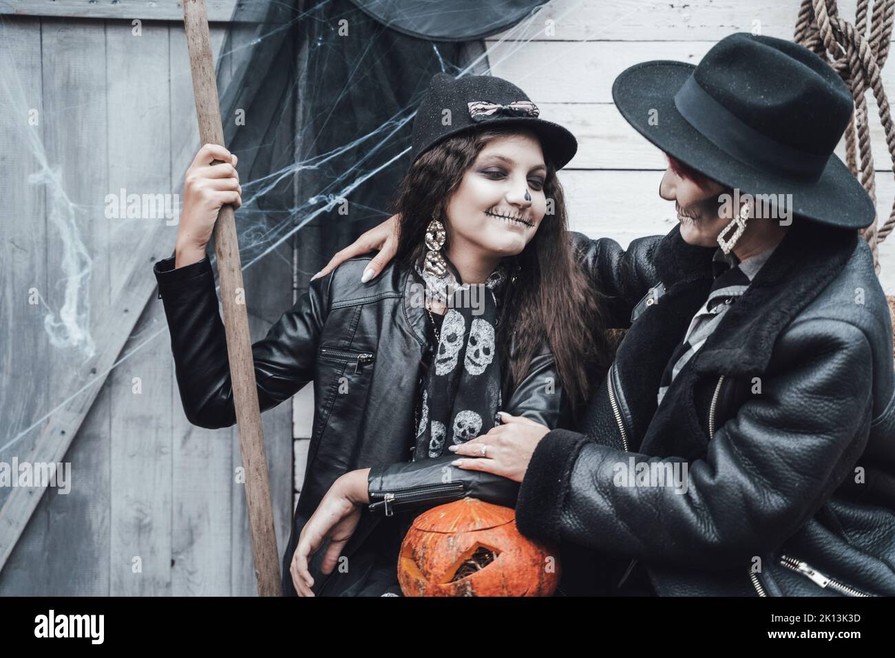 Famiglia spaventosa, madre, figlia che celebra Halloween. Fienile di strada. Zucca jack-o-lantern.terrificante nero cranio mezza faccia trucco e costumi strega, br Foto Stock