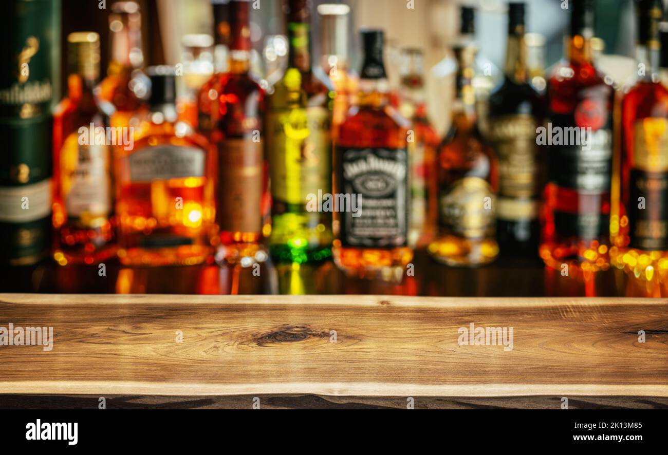 Tavolo in legno e bellissimi ripiani bokeh con bottiglie di alcol sullo sfondo del pub. Concetto di bar. Foto Stock