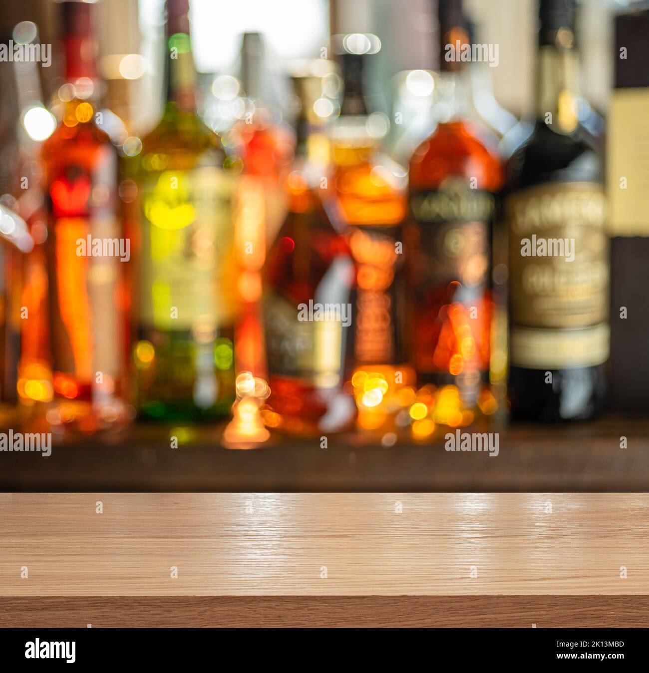 Tavolo in legno e bellissimi ripiani bokeh con bottiglie di alcol sullo sfondo del pub. Concetto di bar. Foto Stock
