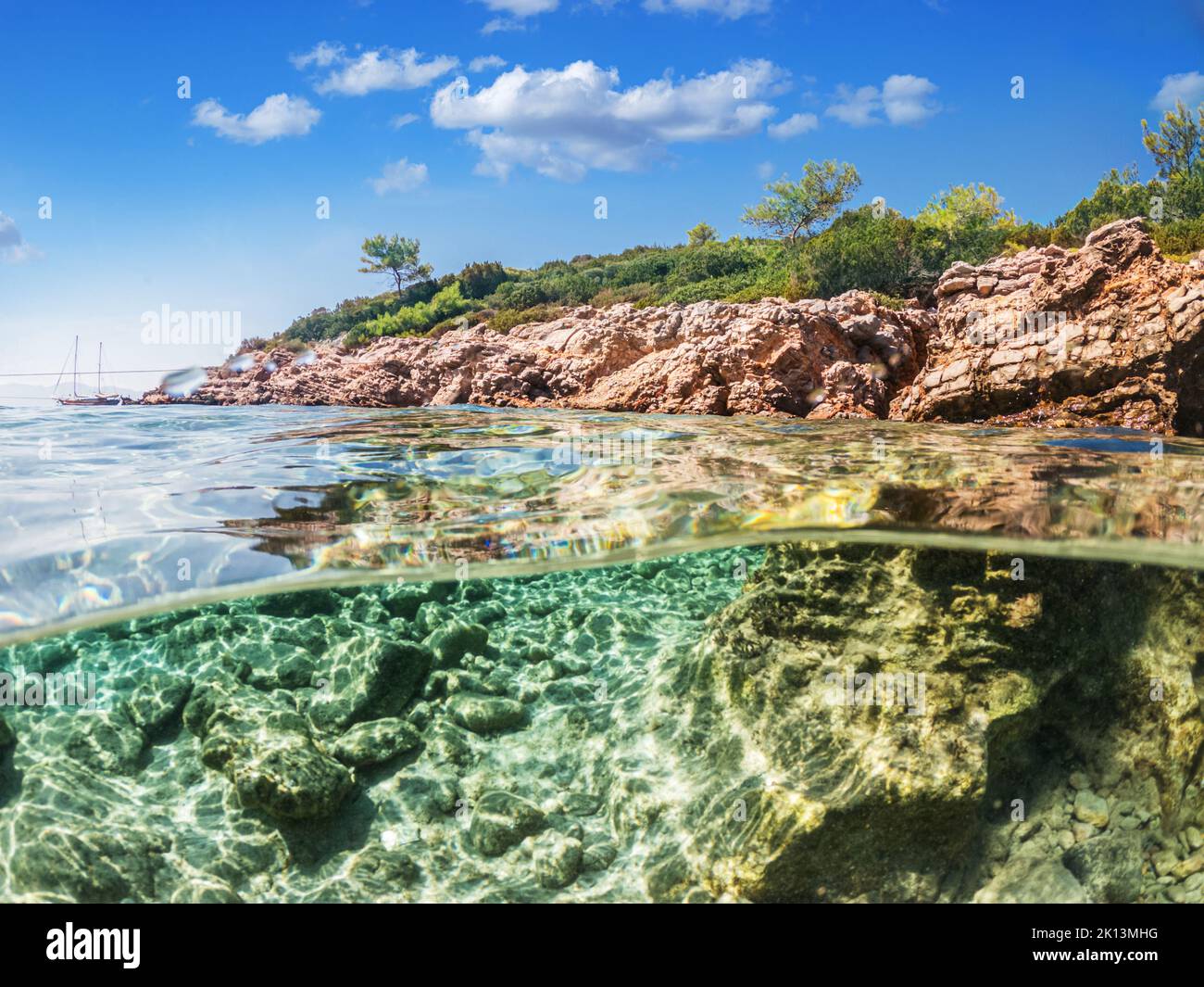 Split view - vista a metà sottomarina di splendidi fondali marini e costa rocciosa con pini, tacchino, Bodrum. Foto Stock