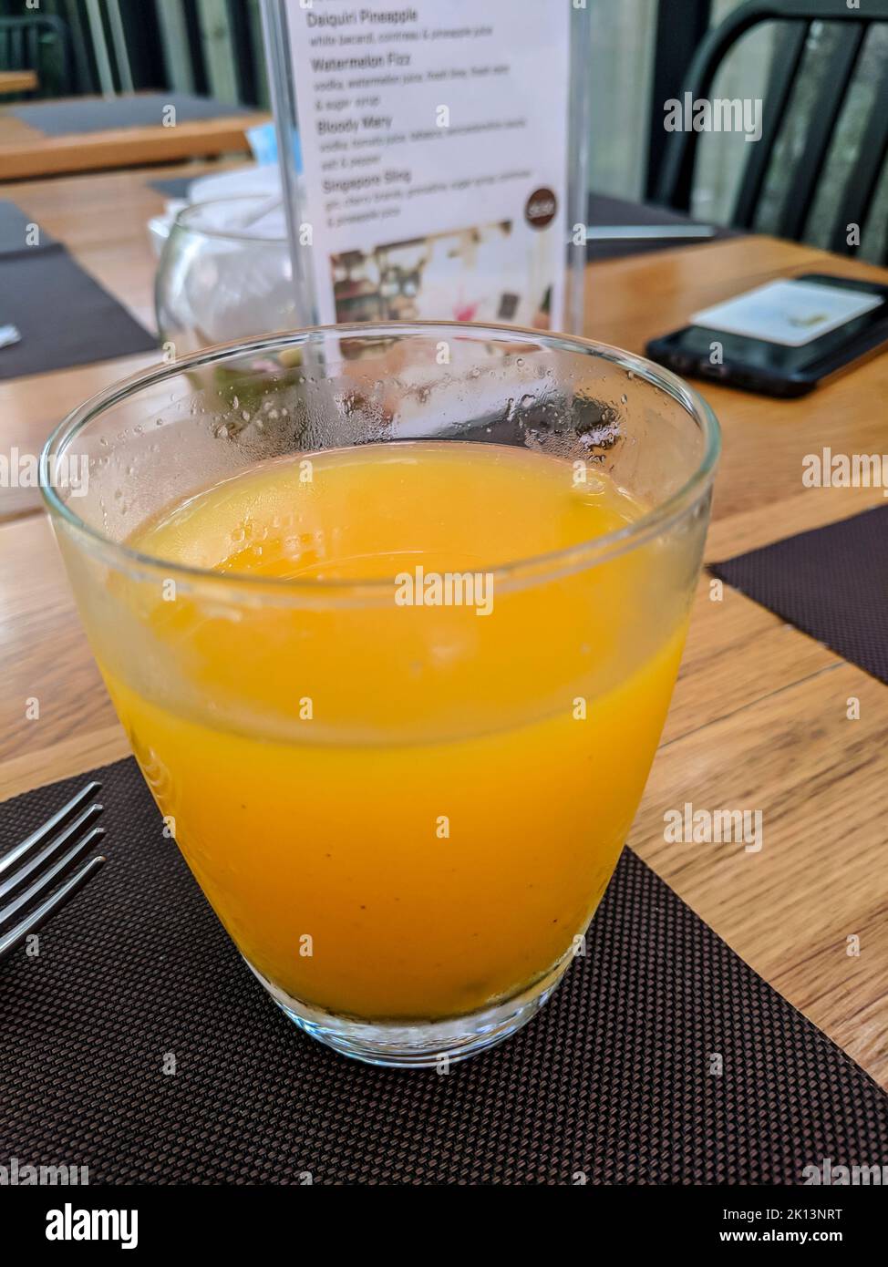 Un bicchiere di succo d'arancia sul tavolo di una caffetteria all'ora della colazione. Foto Stock