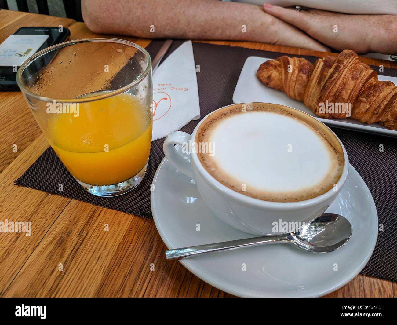 Bicchiere di succo d'arancia, caffè e croissant al tavolo di una caffetteria a colazione. Foto Stock