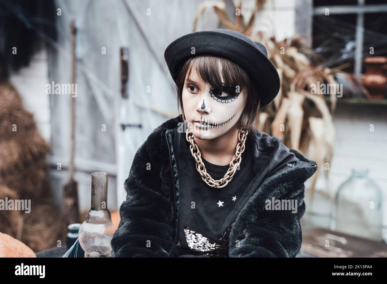 Bella ragazza spaventosa che celebra Halloween. Terrificante nero, bianco mezza faccia trucco e costume strega, immagine elegante. Orrore, divertimento per i bambini Foto Stock