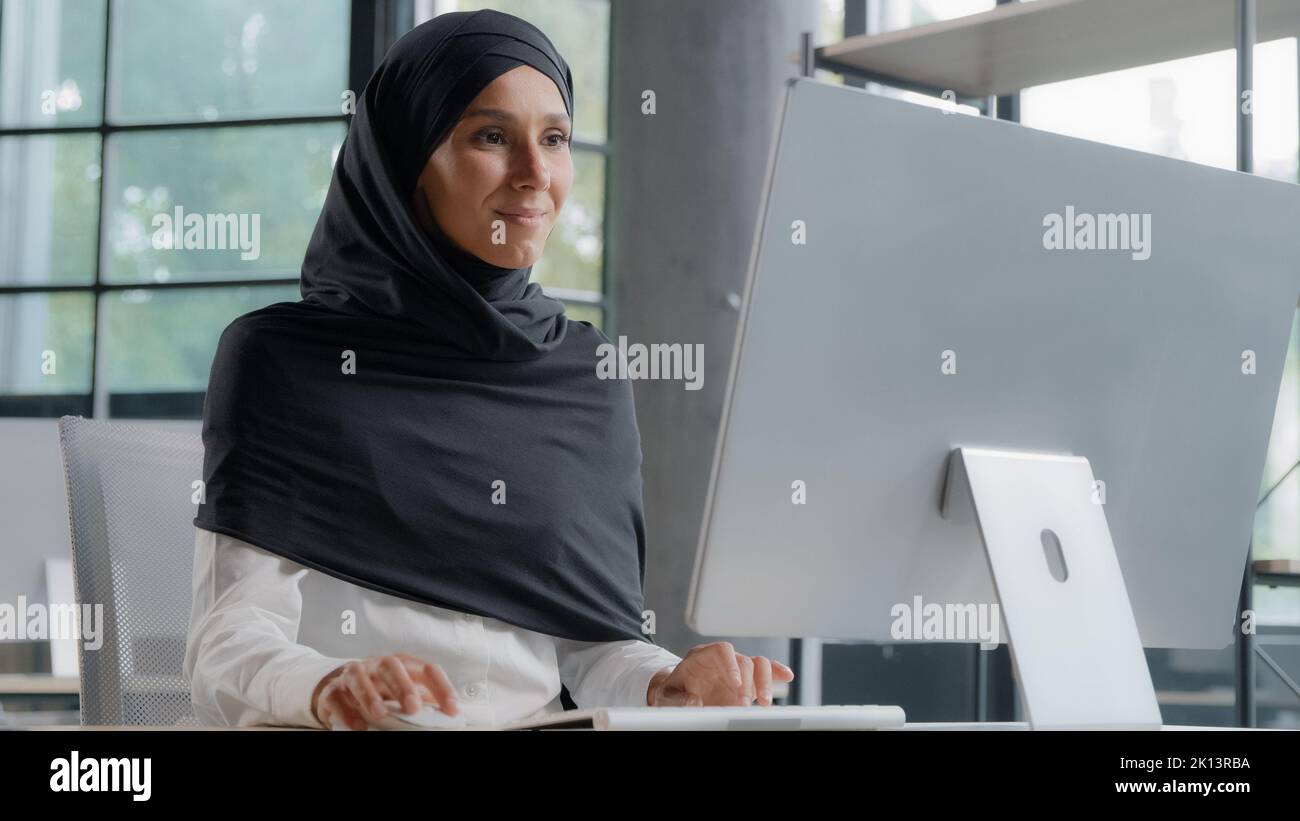Giovane donna d'affari araba in hijab che lavora al computer sorridendo godendo lavoro d'ufficio donna di successo professionale manager azienda dipendente sviluppa Foto Stock
