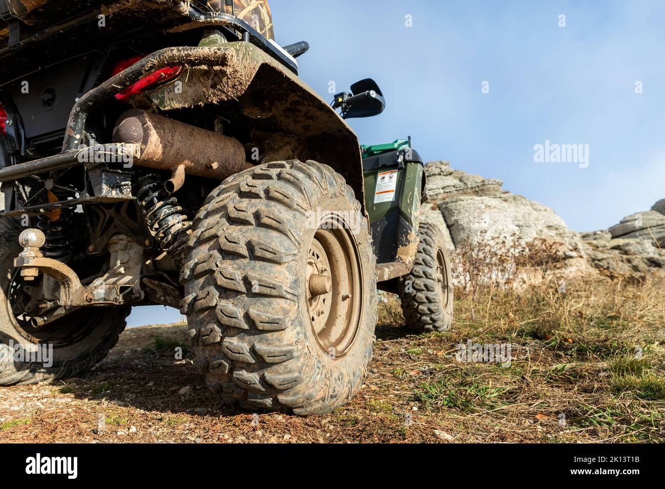 Primo piano dettaglio basso vista POV 4x4 awd veicolo ATV su strada sterrata ghiaiosa non asfaltata in autunno, in cima a una montagna misteriosa. Fuoristrada auto montagna safari avventura Foto Stock