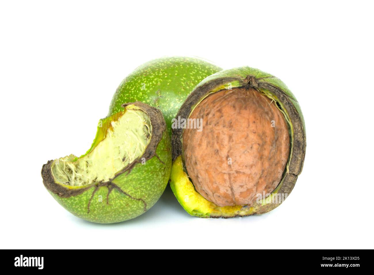 Noce in pericarpo fessurato isolato su fondo bianco. Mucchio di noci in un pericarpo verde Foto Stock