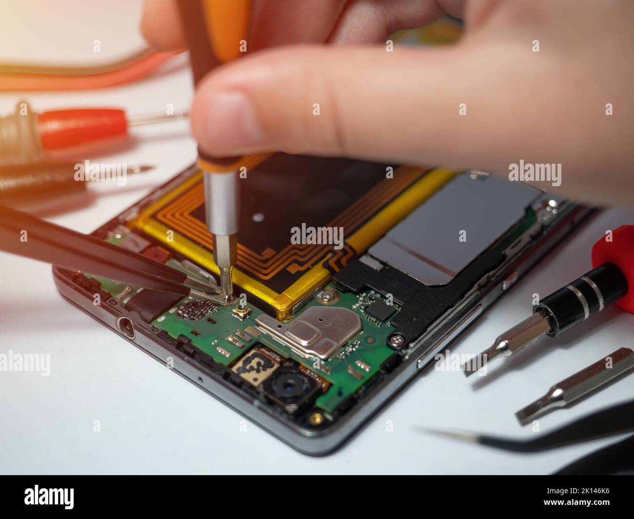 Tecnico dello smartphone che ripara la scheda madre di uno smartphone sulla scrivania del laboratorio di assistenza. Concetto di aggiornamento e riparazione hardware elettronico Foto Stock