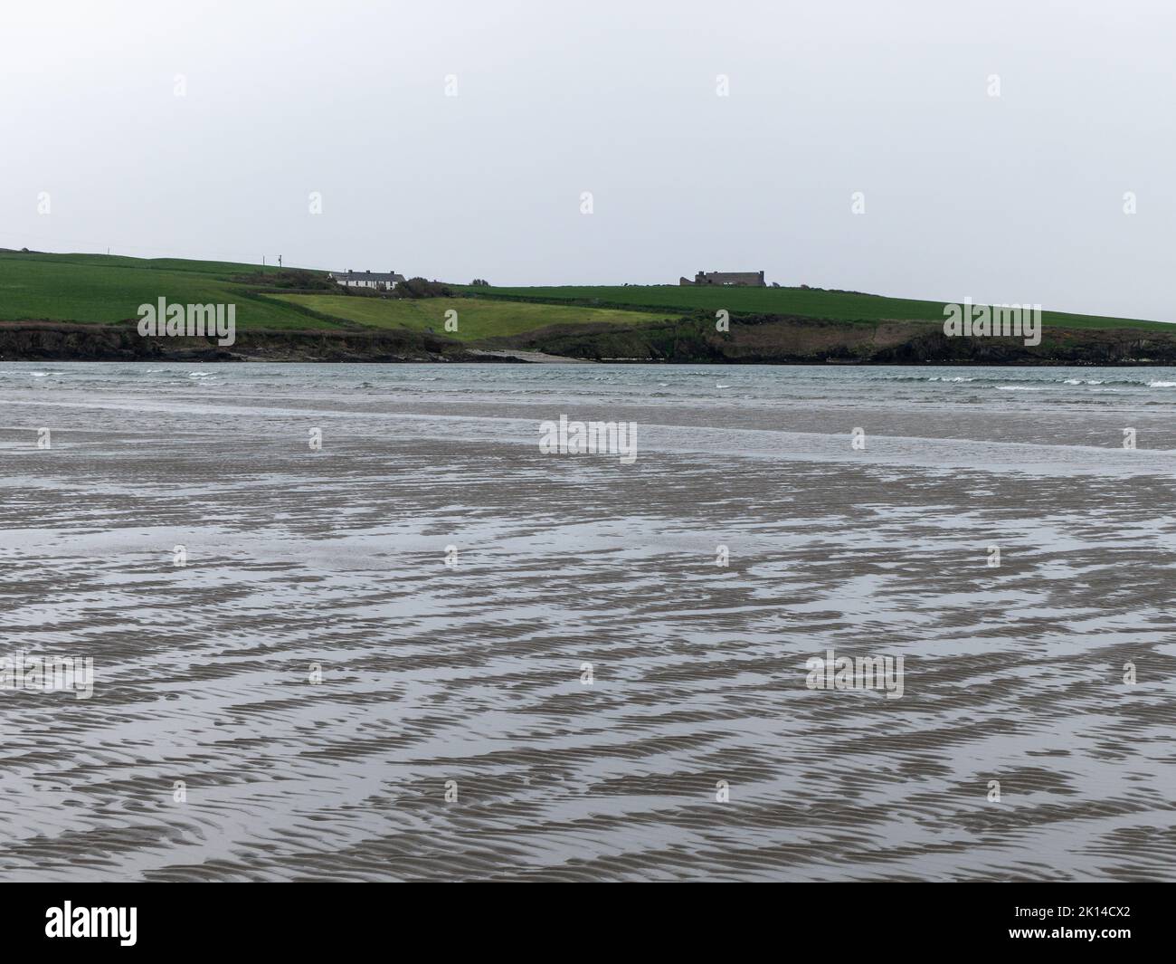 Sabbia ondulata sulla riva di un mare. Paesaggio di mare in una giornata nuvolosa. Splendidi motivi sulla sabbia vicino al corpo d'acqua. Foto Stock