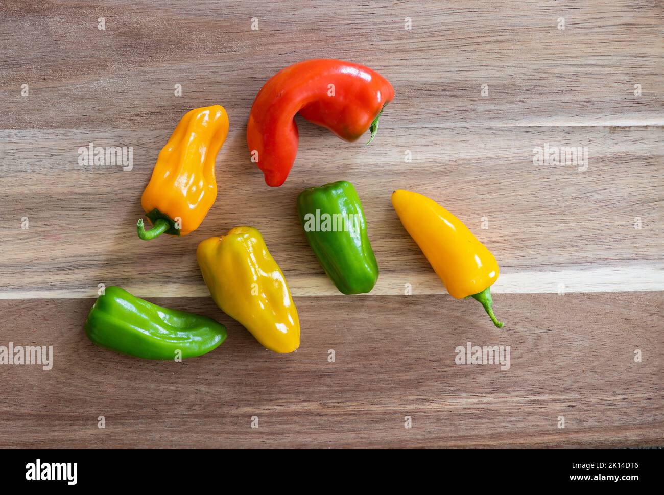 Sei peperoncini biologici molto caldi coltivati in giardino su un tagliere. Foto Stock