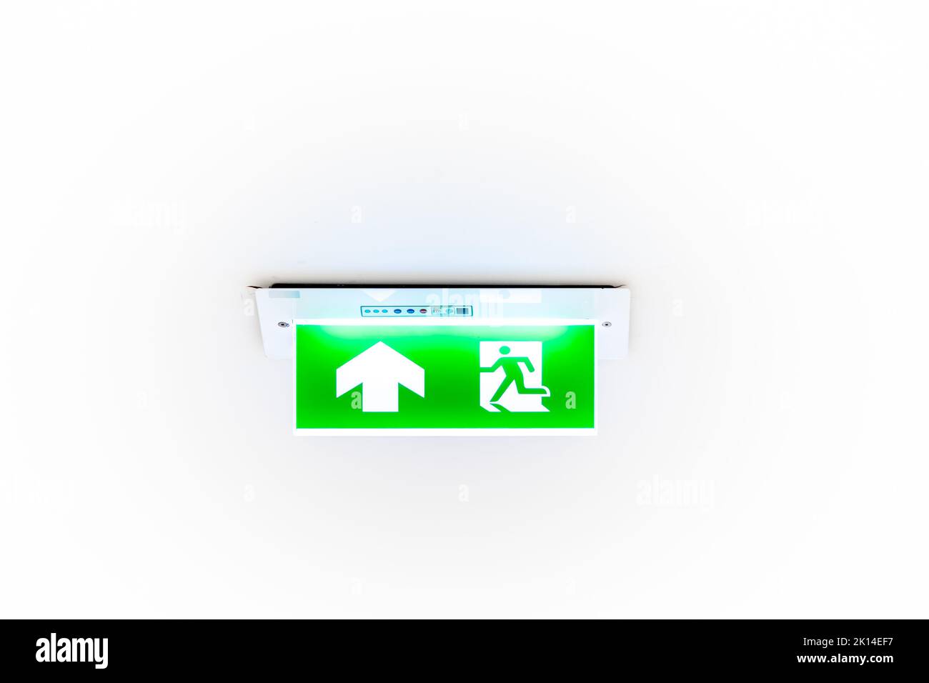 Un cartello al neon bianco raffigurante un'uscita antincendio con sfondo verde è appeso al soffitto. Foto Stock