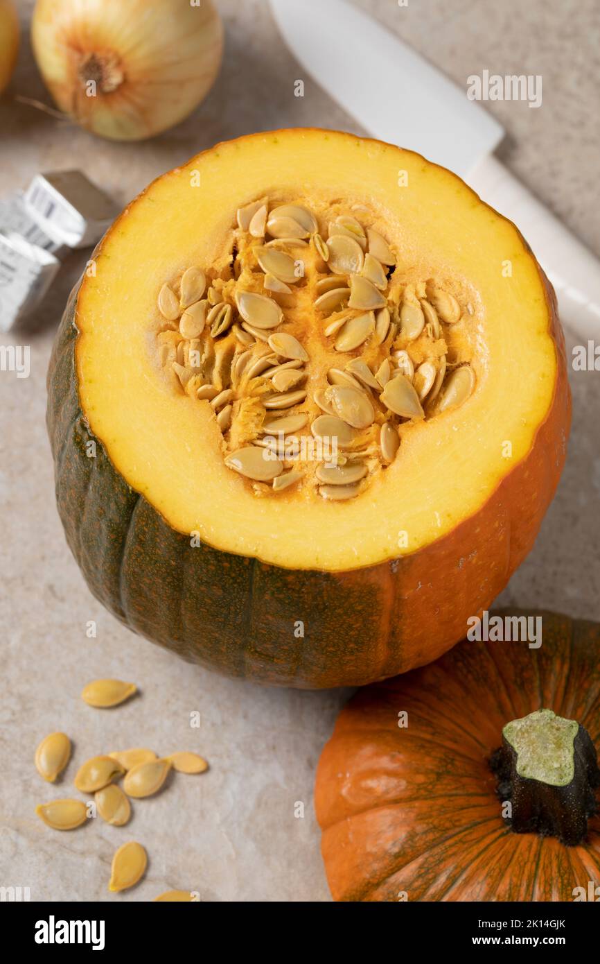 Zucca fresca di Halloween matura e cruda e un taglio visto dall'alto da vicino su un tagliere Foto Stock