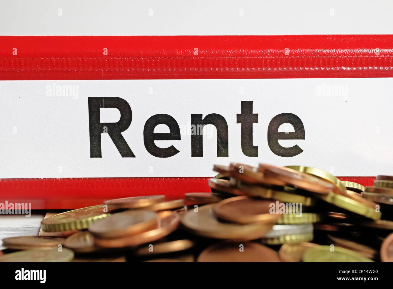 Primo piano di cartelle isolate di file rosso con la parola tedesca Rente (traduzione inglese: pensione), pile di monete in euro Foto Stock