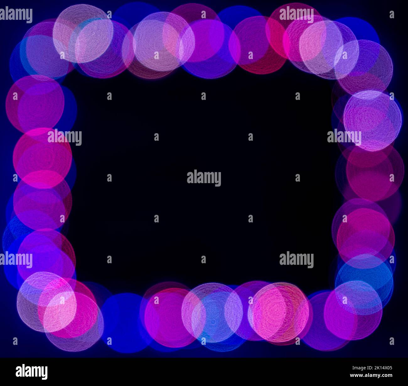 Le luci di natale sfocate viola e blu si illuminano su sfondo scuro Foto Stock