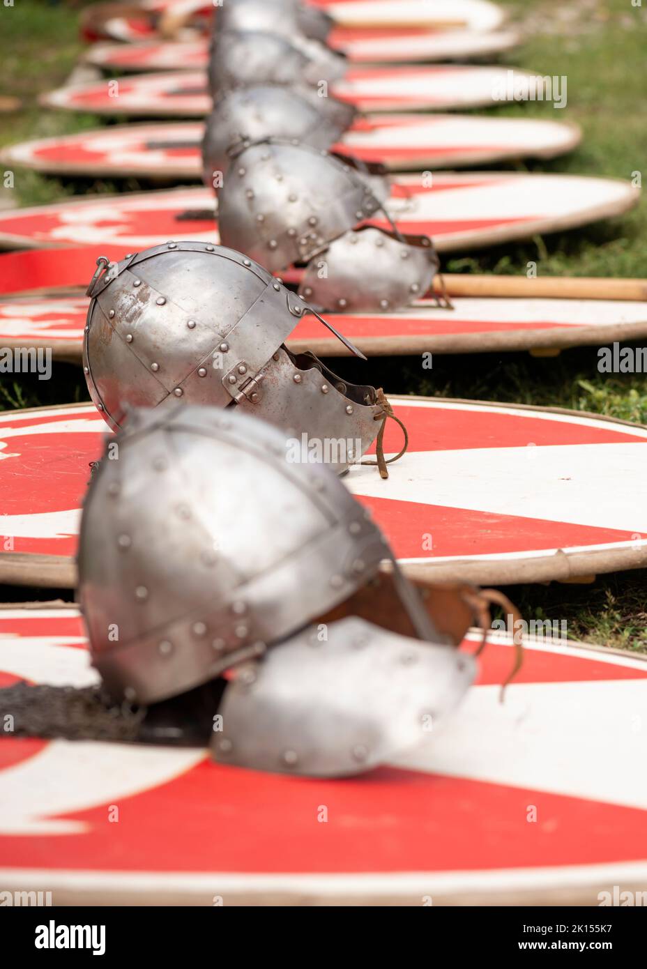 Fila di caschi romani o Galea posto sul terreno durante una rievocazione del festival romano. Foto Stock