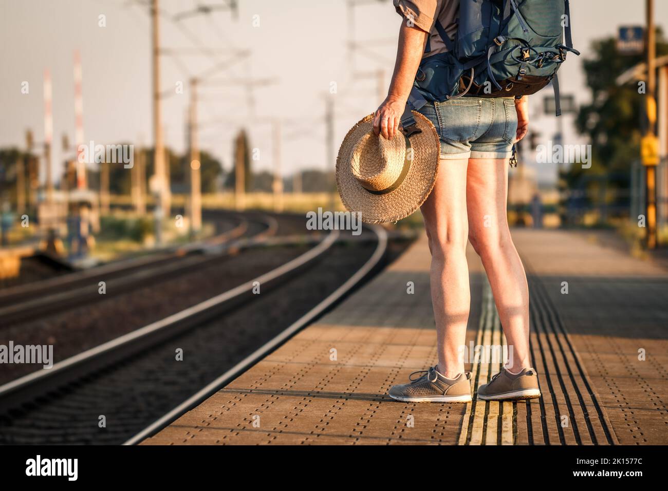 Viaggiatore con zaino e cappello in attesa di treno alla stazione ferroviaria. Donna turista andare in vacanza estiva da solo Foto Stock