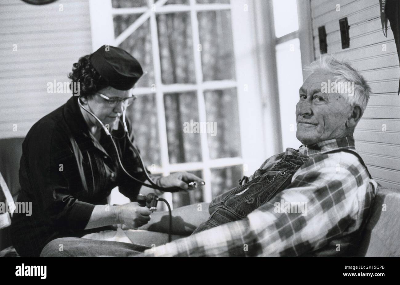 Anna Fox, è stata la prima infermiera della contea nelle montagne del North Carolina occidentale, portando assistenza medica a persone che non avevano mai visto un medico. Qui, controlla la pressione sanguigna di un uomo. Foto Stock