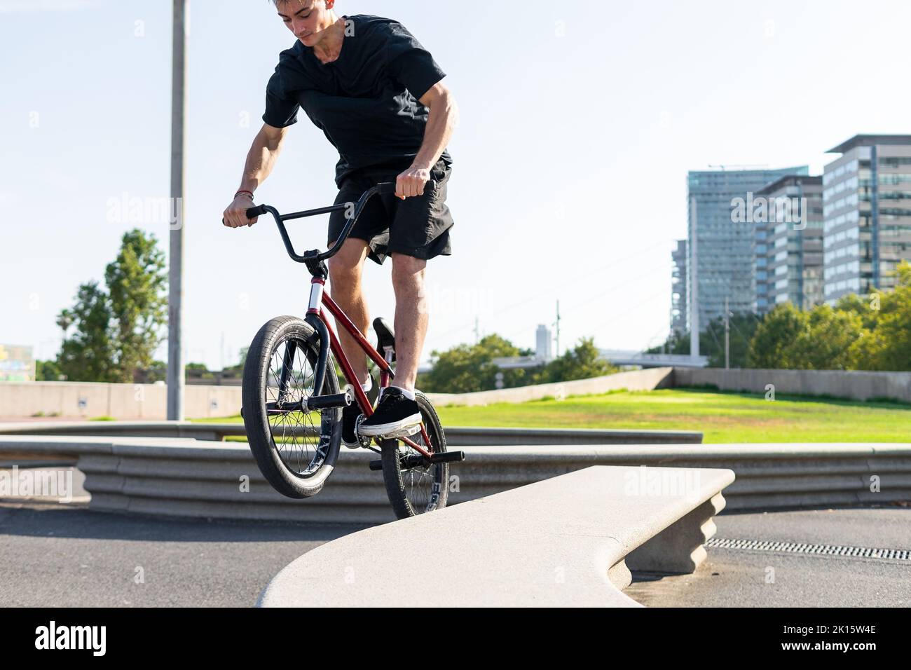 Ritaglia giovane maschio in bicicletta BMX a bordo del confine durante il giorno soleggiato del fine settimana sulla strada della città in estate Foto Stock