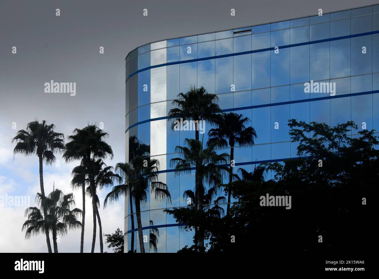 Il cielo minaccioso e tempestoso dietro l'hotel moderno riflette il cielo blu nei suoi esterni in vetro, Miami, Florida, USA Foto Stock