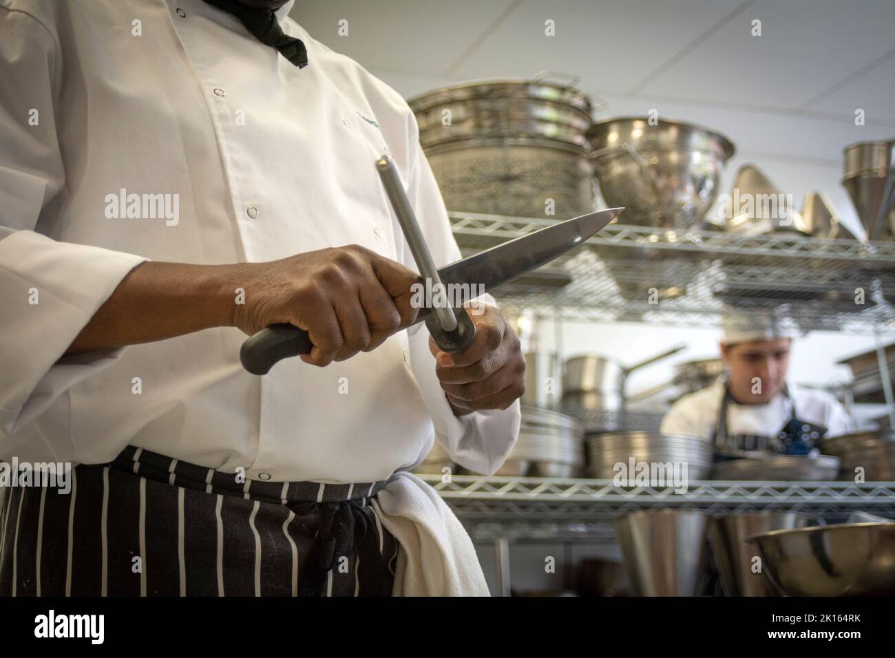 uno chef affilò il coltello per preparare e tritare le verdure nella cucina del ristorante Foto Stock