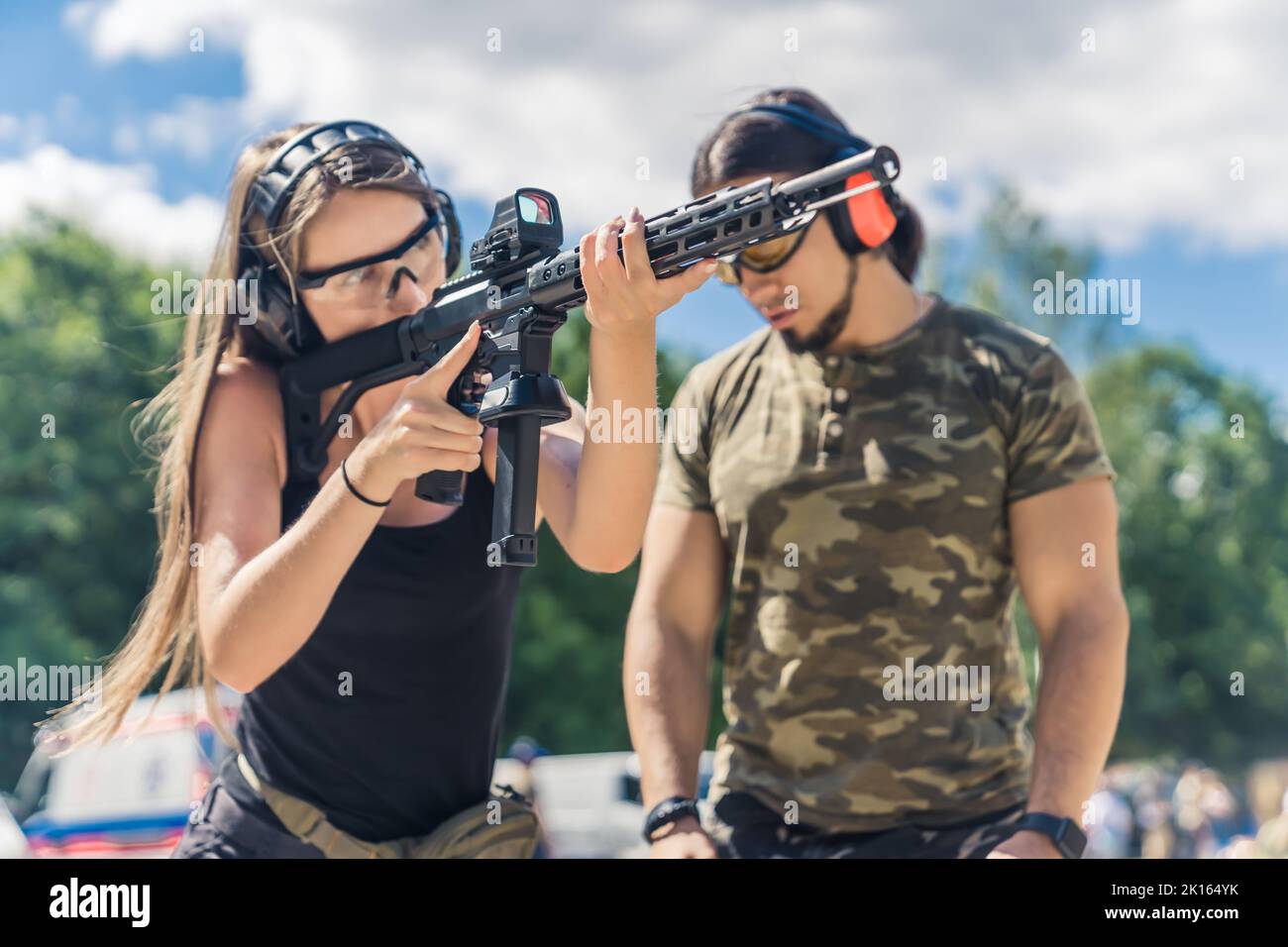 istruttore di sesso maschile che presta attenzione ad una giovane donna che pratica il puntamento con un fucile, tiro fuori campo. Foto di alta qualità Foto Stock