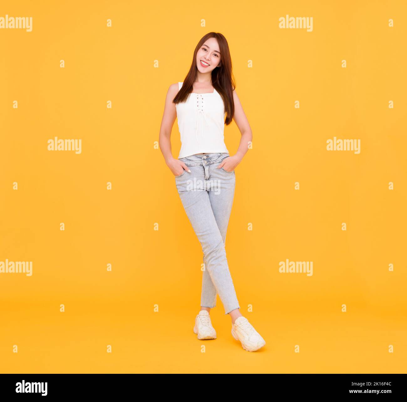 Tutta la lunghezza della giovane donna felice in piedi isolata sopra il giallo Foto Stock