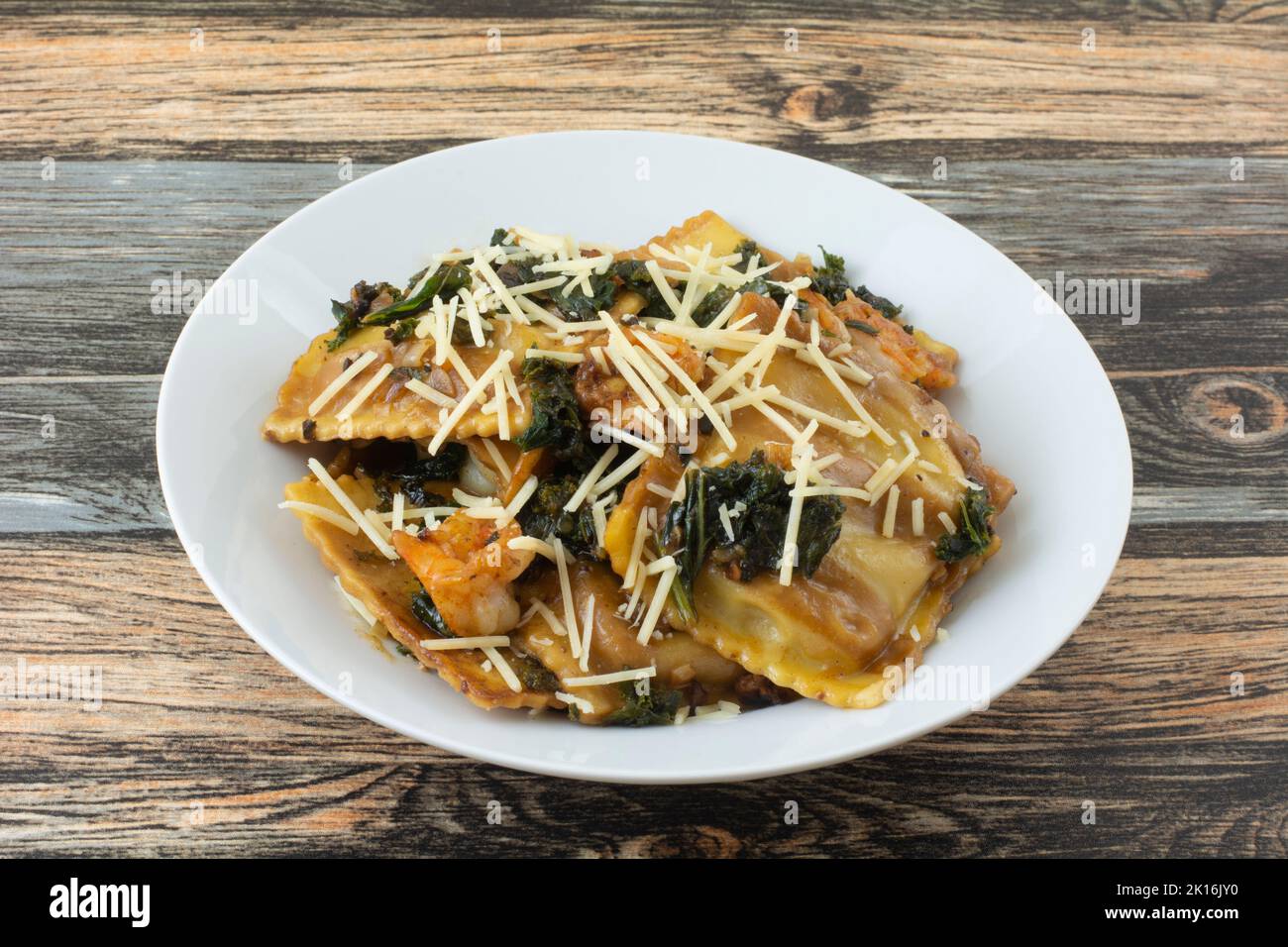 Ravioli di funghi e formaggio con kale e gamberi in ciotola bianca Foto Stock