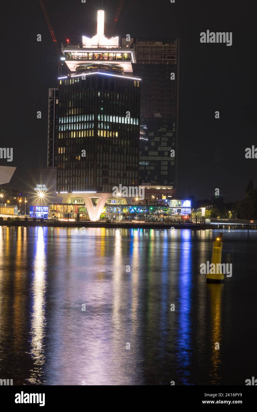 Amsterdam bei Nacht - splendida architettura con riflessi colorati sul lungomare durante la notte. Foto Stock