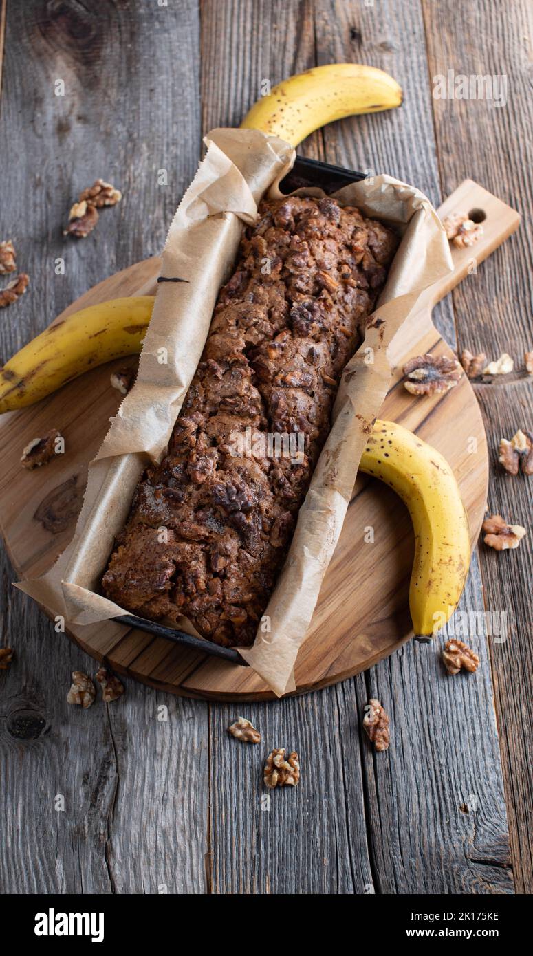 Pagnotta di pane fresco banano con noci in una teglia isolata su un tavolo di legno Foto Stock