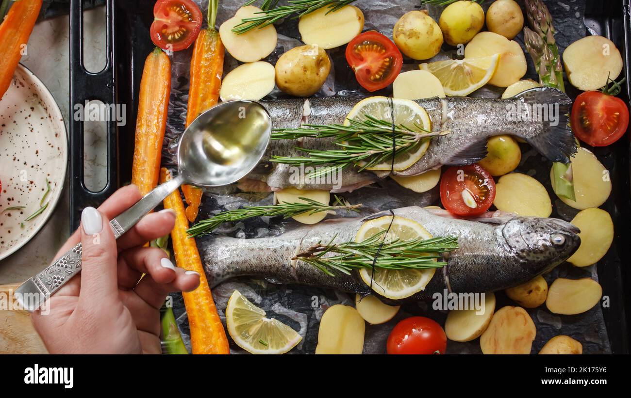 Preparazione del pesce di spigola per la cottura alla griglia con erbe aromatiche e verdure su tavola di legno vista dall'alto Foto Stock