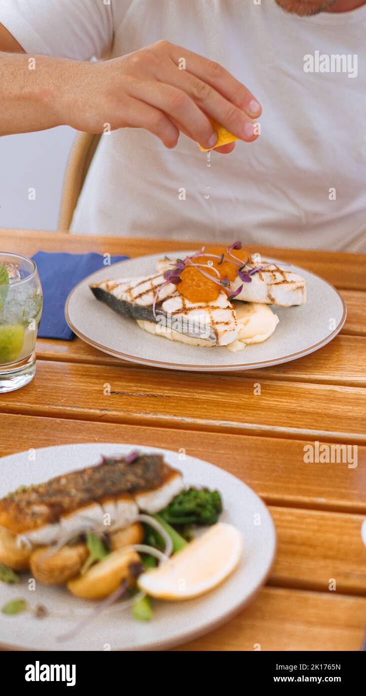 Pasto di pesce con verdure e patate, spremendo il limone per aggiungere un tocco finale. Un bel ristorante di pesce con ottimi pasti nel Queensland. Foto Stock