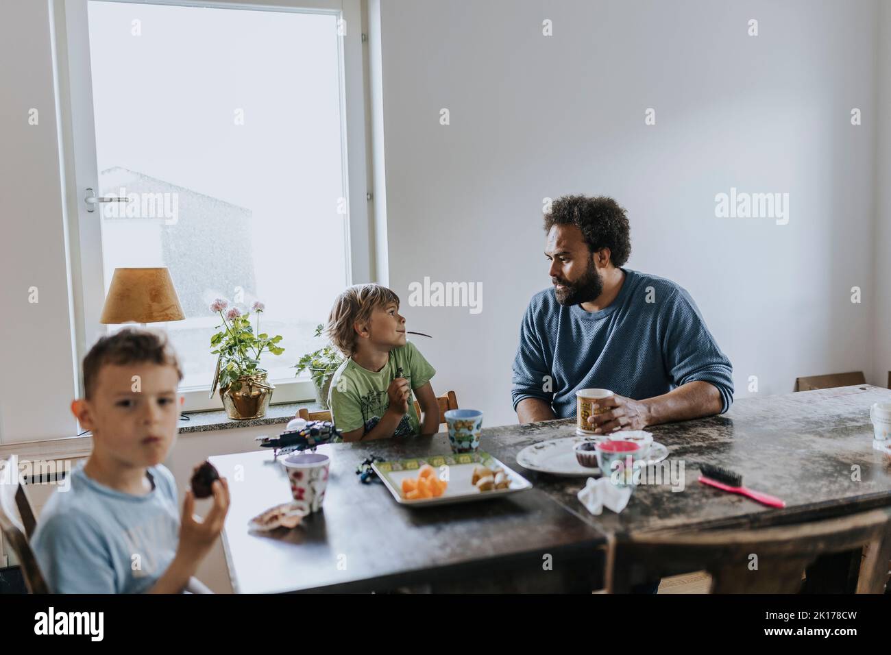 Il padre e i bambini mangiano a tavola Foto Stock