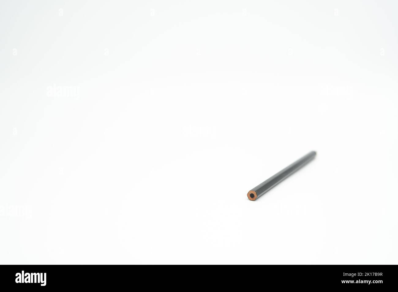 Matita nera di legno su sfondo bianco con estremità a fuoco Foto Stock