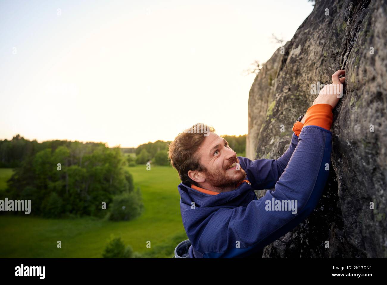 Uomo sorridente arrampicata su roccia Foto Stock