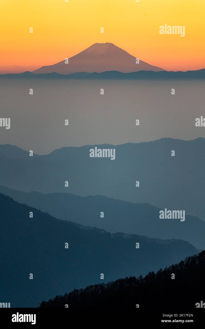 Uno scatto verticale del Monte Fuji sotto il cielo arancione del tramonto in Giappone Foto Stock