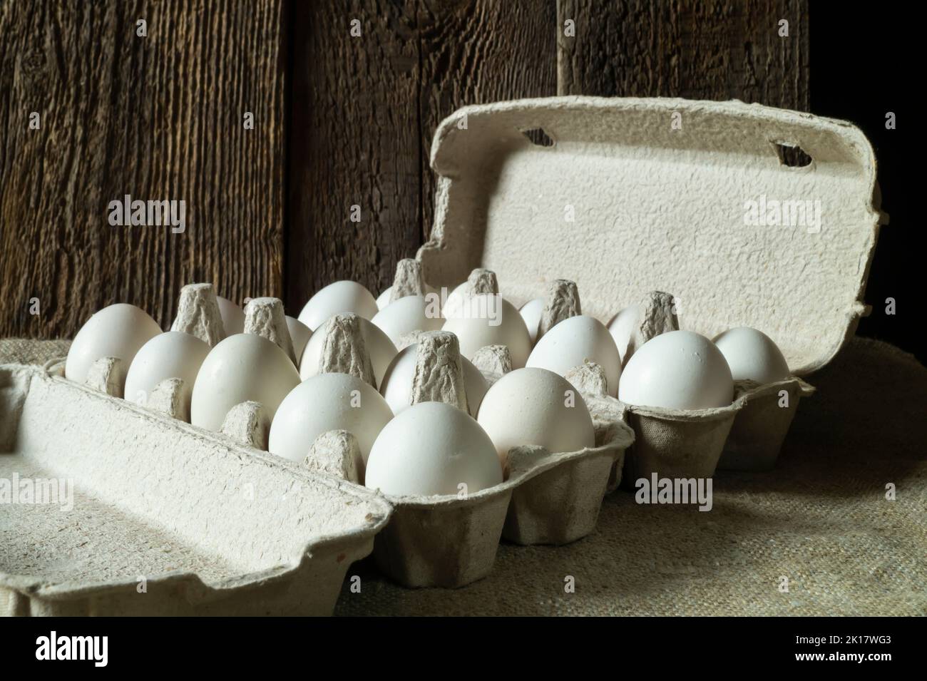 Vita morta con le uova in imballaggi ecologici di cartone. Cibo su sfondo scuro. Foto Stock
