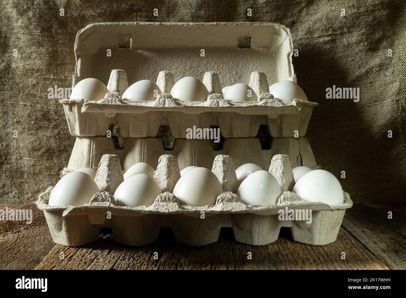 Vita morta con le uova in imballaggi ecologici di cartone. Cibo su sfondo scuro. Foto Stock