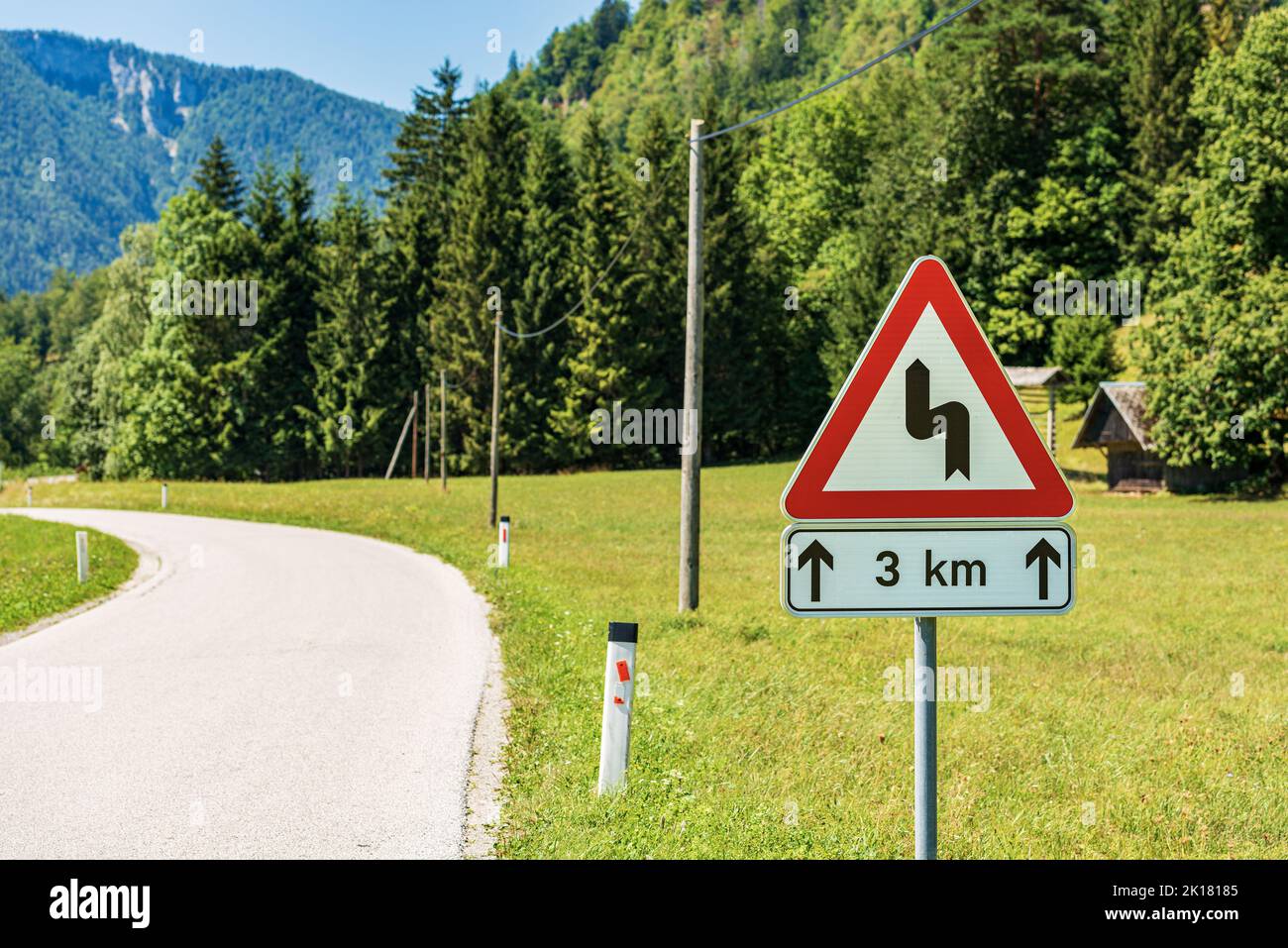 Segnaletica stradale triangolare bianca e rossa di strade tortuose che precedono, strada di montagna con serie di curve pericolose per tre chilometri. Slovenia, Europa. Foto Stock