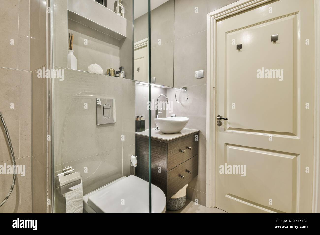 Divisorio in vetro tra il rubinetto della doccia e la toilette appesa alla parete nella moderna stanza da bagno di casa Foto Stock