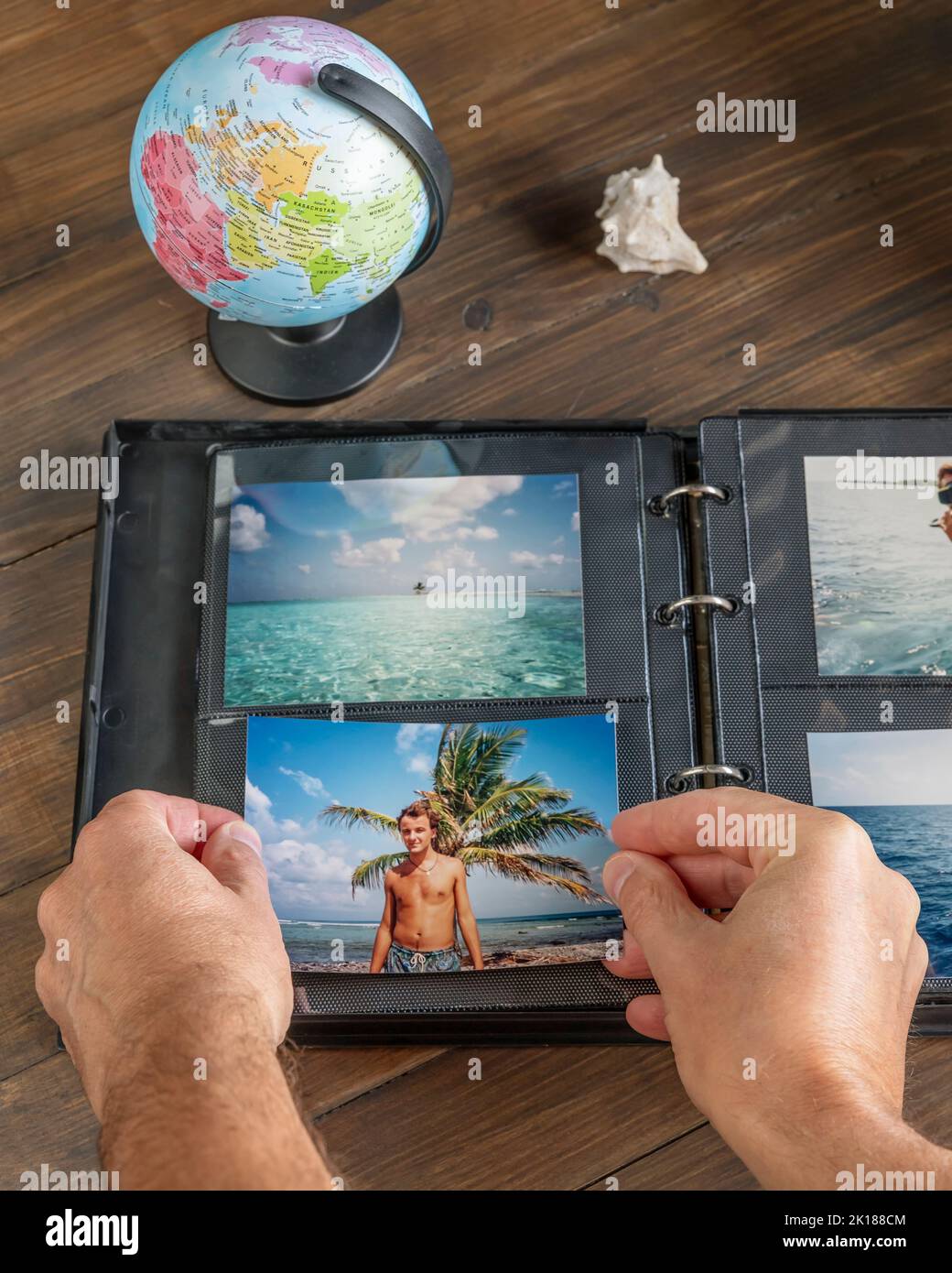 Le mani maschili aggiungono una nuova foto in un album fotografico con anelli di apertura Foto Stock