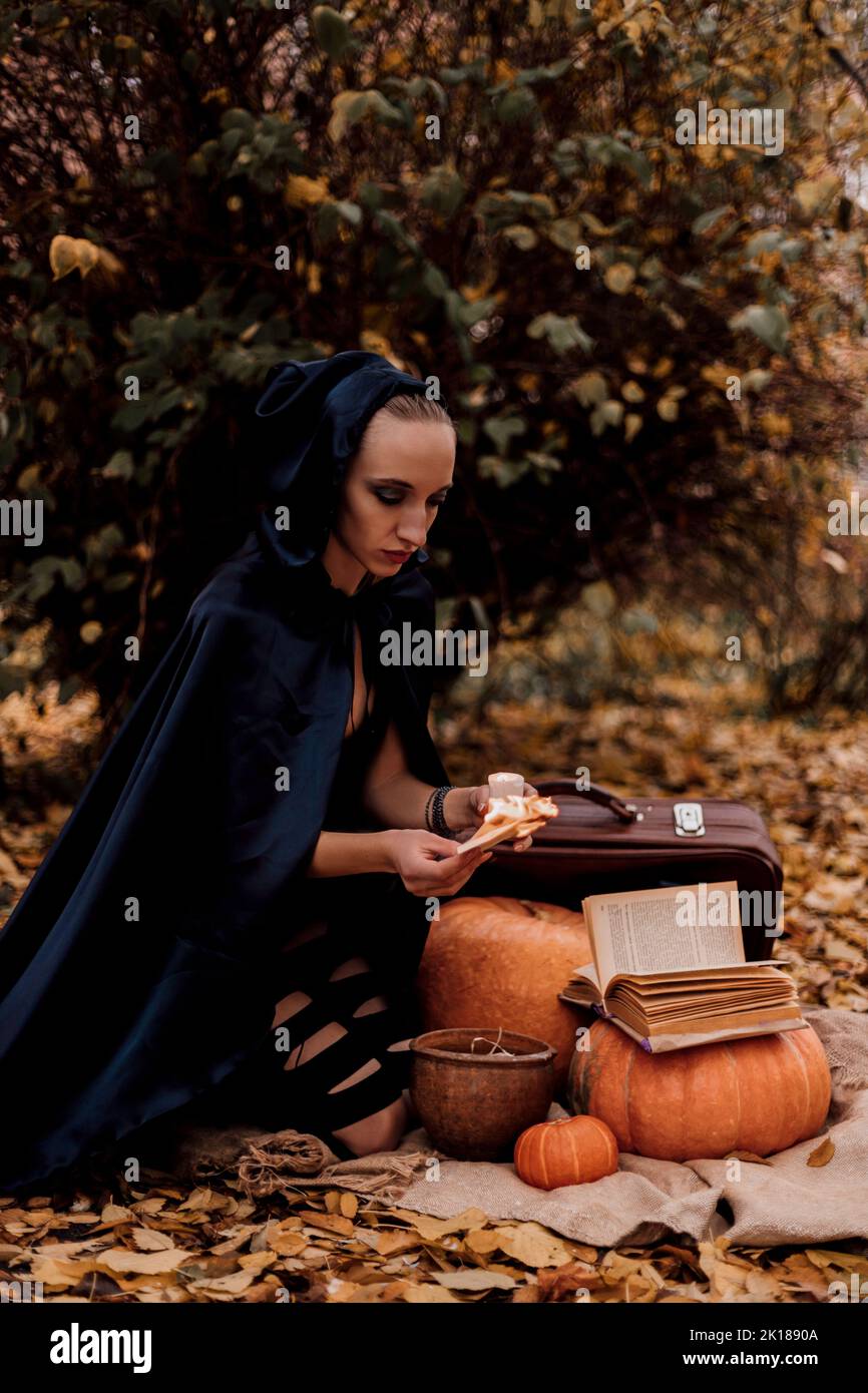 Una giovane donna nei boschi pratica la magia di Halloween Foto Stock